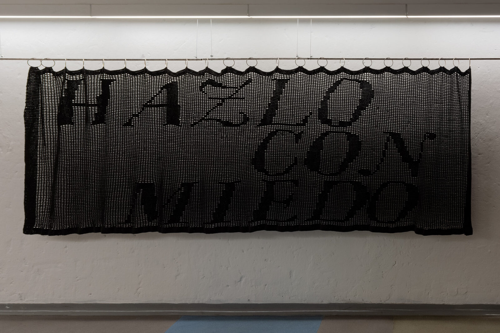 Hazlo con miedo — instalación textil calada en negro con el texto tejido en crochet fillet