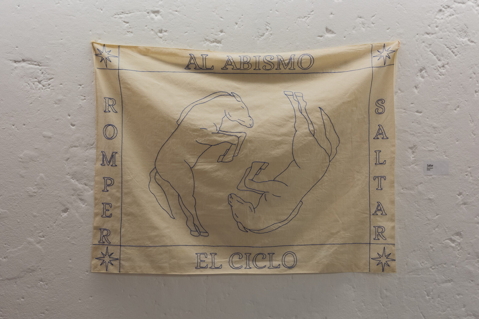 Saltar — tapiz bordado con dos figuras de cabra y el texto Romper al abismo el ciclo saltar